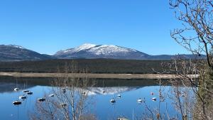 a snow covered mountain is reflected in a lake at Camping de Cervera de Buitrago in Cervera de Buitrago