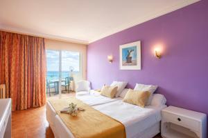 um quarto de hotel com uma cama grande e uma parede roxa em BJ Playa Blanca em Sa Coma