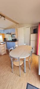 a table and chairs in a room with a kitchen at Mobil Home 3 chambres 6 pers 1/2h PUY du FOU in La Boissière-de-Montaigu