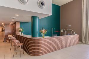 a lobby with a bar with a green wall at NAU Sao Rafael Suites - All Inclusive in Albufeira