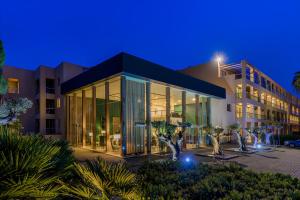 a building with a lot of glass at night at NAU Sao Rafael Suites - All Inclusive in Albufeira