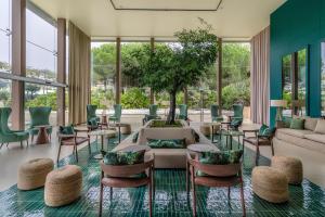 a living room with a couch and chairs and a tree at NAU Sao Rafael Suites - All Inclusive in Albufeira
