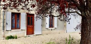 a house with red and white doors and a tree at MAT TRANG in Mars-sur-Allier