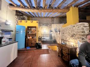 a man sitting in a kitchen with a blue refrigerator at El Rinconcito in Fuentespalda