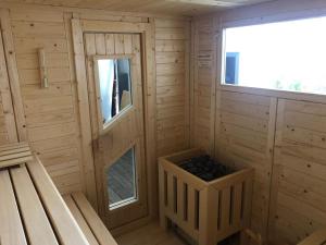 una sauna de madera con ventana y una cesta de carbón en Apartment house Calmsailing B rgerende, en Börgerende-Rethwisch