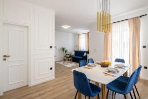 uma sala de jantar com uma mesa branca e cadeiras azuis em VIPo Seget Apartments em Trogir