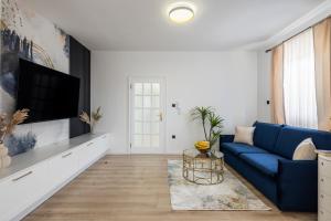 uma sala de estar com um sofá azul e uma televisão em VIPo Seget Apartments em Trogir
