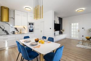 a kitchen and dining room with a white table and blue chairs at VIPo Seget Apartments in Trogir