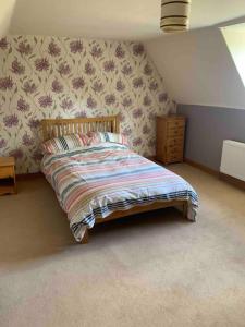 ein Bett in einem Schlafzimmer mit einer Wand in der Unterkunft Gullers End Farm Cottage in Long Green