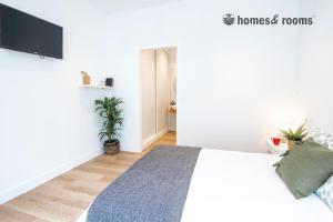 a white bedroom with a bed and a flat screen tv at Enorme apartamento con 4 baños in Santiago de Compostela