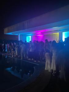 una folla di persone che si trovano di fronte a un edificio di notte di Events Hause a Gammarth