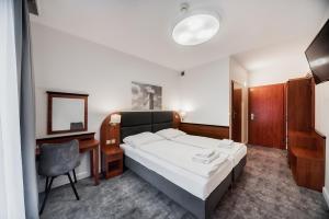 a bedroom with a bed and a desk and a chair at Rezydent Resort in Świnoujście