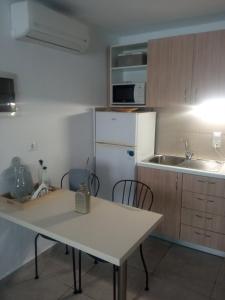a kitchen with a table and a white refrigerator at Rosemary Apartment in Exopoli, Georgioupolis in Exopoli