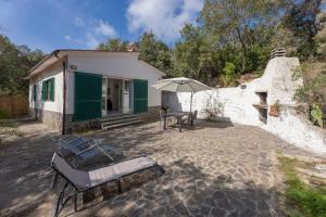 a patio with chairs and an umbrella in front of a house at Villino Straccoligno - Goelba in Capoliveri