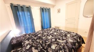 a bedroom with a black and white bed with blue curtains at L'industriel - Tout confort in Saint-Brieuc