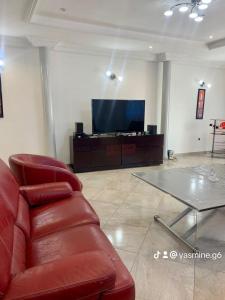 uma sala de estar com um sofá de couro vermelho e uma televisão em Yasmine Immo em Cotonou