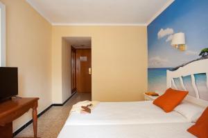 a hotel room with a bed and a painting of the ocean at BJ Hostal Bona Vista in S'Illot