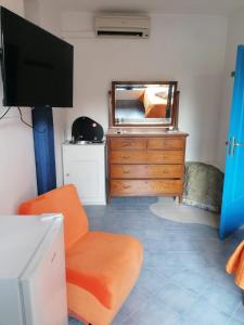 - un salon avec une télévision, une chaise et une commode dans l'établissement Dimora Coloniale B&B, à Ischia