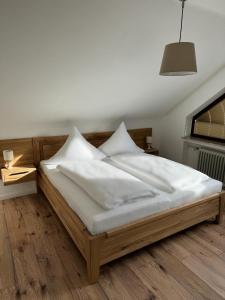 Bett mit weißer Bettwäsche und Kissen in einem Zimmer in der Unterkunft Haus Cornelia in Einruhr