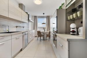 a kitchen with white cabinets and a table with chairs at LAM City Jungle - SKY VIEW 21 FLOOR - Free Parking in Bratislava