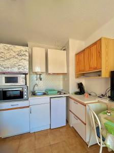 una pequeña cocina con electrodomésticos blancos y armarios de madera. en Vamos a PIEDS DANS L EAU Linges de maison inclus, en Empuriabrava