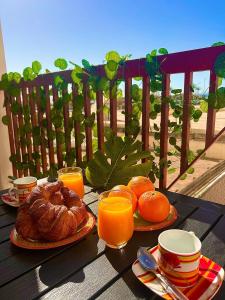 een tafel met brood en sinaasappels en glazen sinaasappelsap bij Vamos a PIEDS DANS L EAU Linges de maison inclus in Empuriabrava