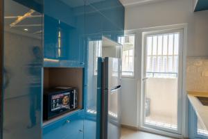 cocina azul con nevera y ventana en Elegance Retreat, en Yelahanka
