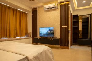 a bedroom with a bed and a flat screen tv at Elegance Retreat in Yelahanka