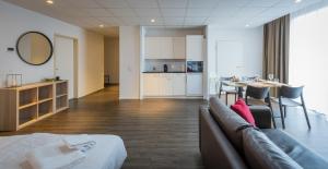 a room with a couch and a table and a kitchen at Los Lorentes Hotel Bern Airport in Belp