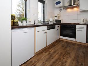cocina con armarios blancos y suelo de madera en Holiday home Luebben, en Lübben