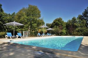 a swimming pool with chairs and umbrellas at Tidy chalet in the woods of the beautiful Dordogne in Souillac