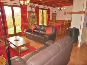 a living room with a leather couch and a table at Tidy chalet in the woods of the beautiful Dordogne in Souillac