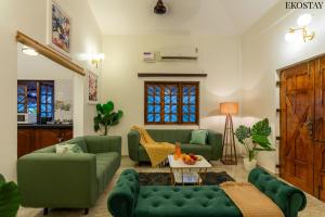 a living room with green couches and a table at EKOSTAY Gold - CASA PORTO Villa in Anjuna