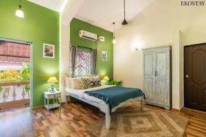 a bedroom with green walls and a bed in a room at EKOSTAY Gold - CASA PORTO Villa in Anjuna