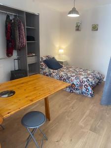 Schlafzimmer mit einem Bett und einem Holztisch in der Unterkunft Studio en plein centre des Vans in Les Vans
