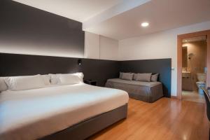 a hotel room with two beds and a bathroom at Sancho Ramirez in Pamplona