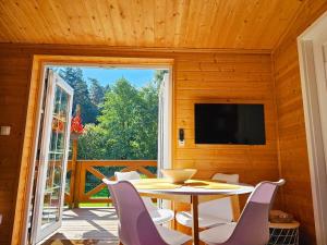 comedor con mesa, sillas y TV en Modraszkowe Domki, en Radków