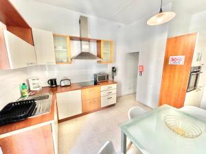 a kitchen with wooden cabinets and a glass table at St Julians - Balluta Bay large 3 bedroom apartment in Sliema