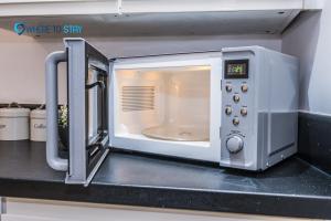 a microwave oven with its door open on a counter at Wheretostay 1 bed apartment Aberdeen in Aberdeen