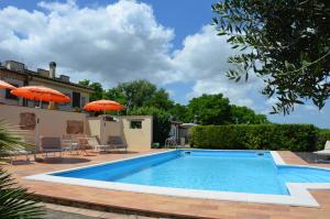a pool with chairs and umbrellas next to a house at agriturismo contrada del raglio in Potenza Picena