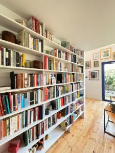 a library with white shelves filled with books at Beautifully Designed 4BD House Peckham London! in London