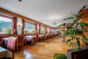 a dining room with tables and chairs and windows at Hotel Des Alpes in Cortina dʼAmpezzo