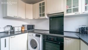 una cucina con armadi bianchi e una lavatrice/asciugatrice di Appartement 60m² à 20 min de Paris a Romainville