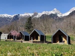 uma fila de cabanas num campo com montanhas ao fundo em Base camp - Apartments & Rooms em Bovec