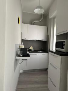 eine Küche mit weißen Schränken und einer Mikrowelle in der Unterkunft Casa Sophia in Omegna
