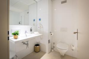 a white bathroom with a toilet and a sink at Los Lorentes Hotel Bern Airport in Belp