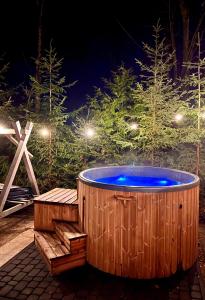 uma banheira de hidromassagem de madeira com um banco e árvores à noite em Mazursko - domy em Kretowiny