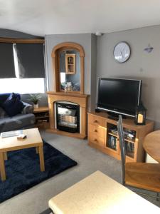 een woonkamer met een tv en een open haard bij THE VAN in Porchfield