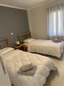 Deppys Apartment Porto Heli في بورتوخيلي: غرفة نوم بسريرين عليها مناشف