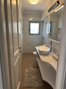 uma casa de banho branca com um lavatório e um espelho em Deppys Apartment Porto Heli em Porto Heli